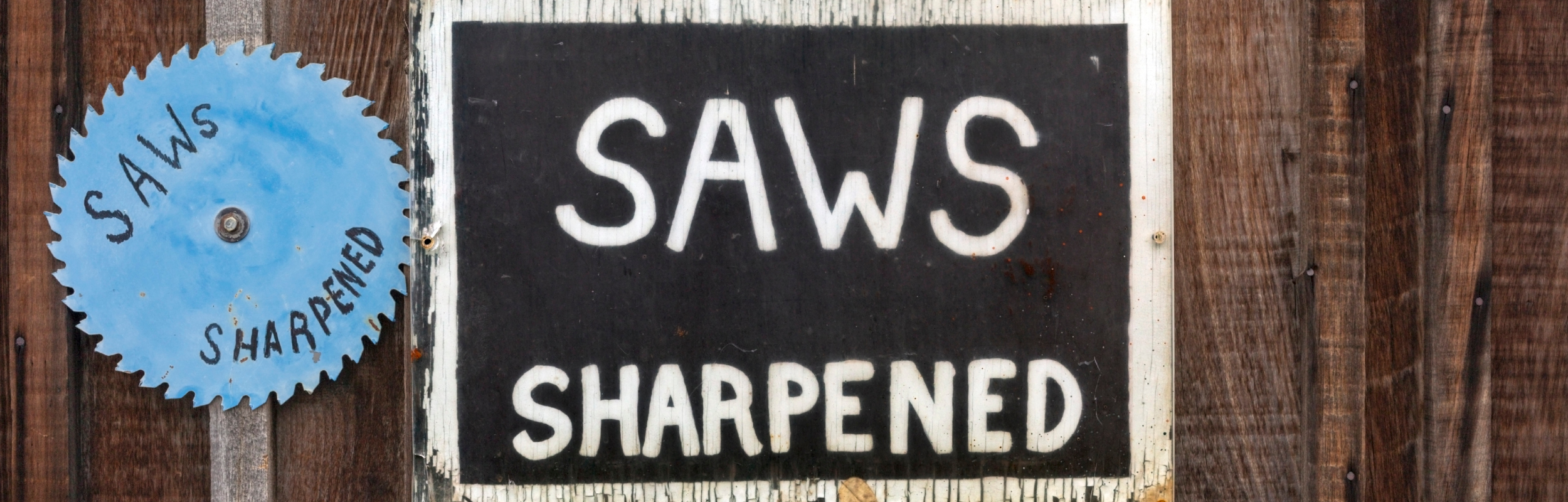 SAWS SHARPENED signs mounted on exterior wood building