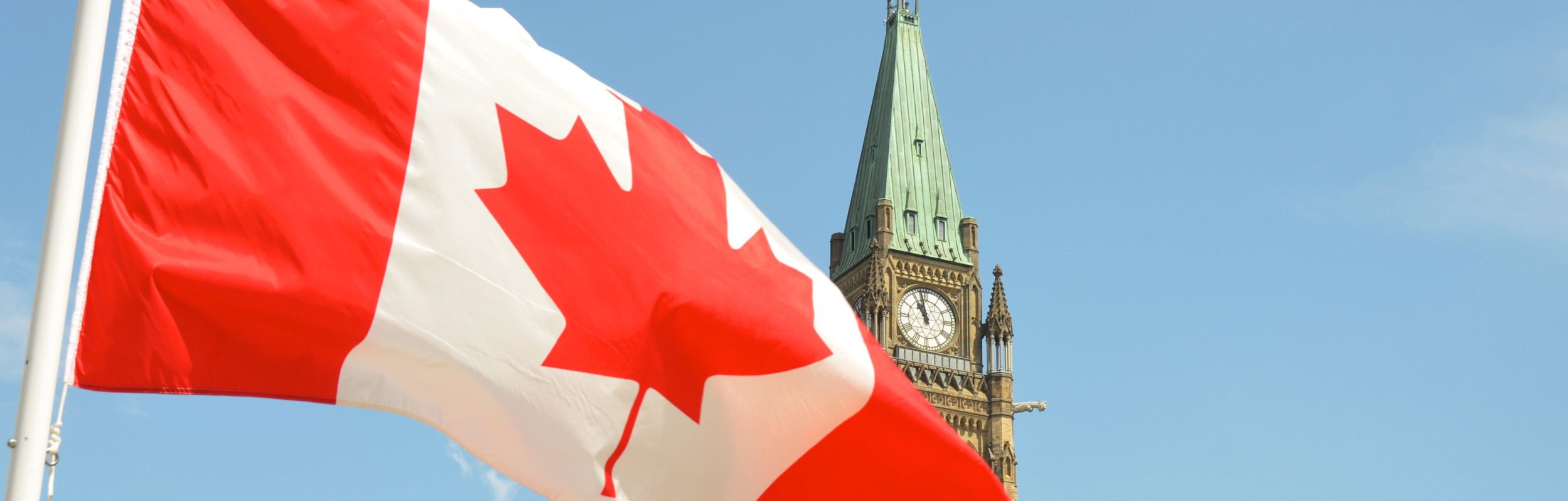 Canadian flag with the Peace Tower of the Parliament building in the background